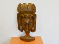 Stylized wooden face sculpture with crown, showcasing intricate craftsmanship and cultural significance.