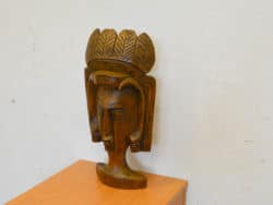 Intricate wooden sculpture of a serene face with a leaf crown, reflecting cultural artistry.