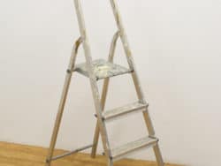 Vintage aluminum step ladder with wear, ideal for household tasks and painting projects.