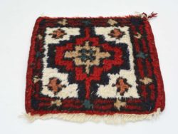 Handwoven deep red rug featuring a star motif and floral patterns for cultural elegance.