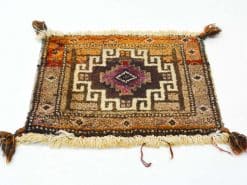 Handwoven vintage rug with geometric patterns in warm earthy tones and tassel details.