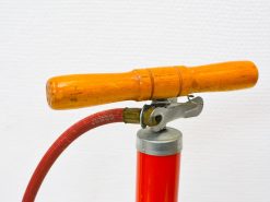 Vintage red hand pump with wooden handle, perfect for bike inflation and retro decor.