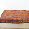 Vibrant handmade orange and blue rug with intricate geometric patterns and rich texture.