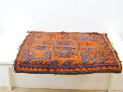 Vibrant handmade orange and blue rug with intricate geometric patterns and rich texture.