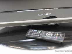 Sleek Sharp TV with remote control enhances modern living room entertainment and style.