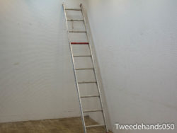 Sleek aluminum ladder against a white wall, enhancing a minimalist space with warm wooden flooring.