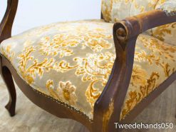 Elegant vintage armchair with luxurious floral pattern in beige and gold for stylish interiors.