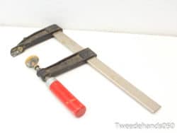 Vintage C-clamp with red handle, ideal for woodworking and metalworking tasks.