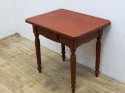 Charming vintage wooden table with turned legs and drawer, ideal for cozy gatherings.