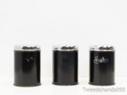 Stylish black canisters with shiny lids, ideal for organizing sugar, nuts, and spices.