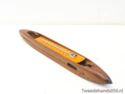 Elegant wooden weaving shuttle with orange measuring tape for precise textile crafting.