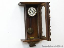 Elegant vintage wall clock with pendulum, Roman numerals, and intricate wood carvings for timeless decor.