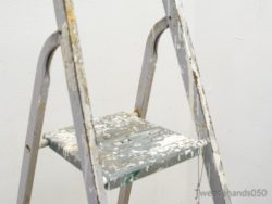 Weathered stepladder with paint splatters, ideal for vintage decor and creative spaces.