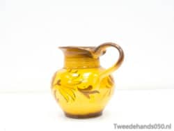 Vibrant yellow ceramic pitcher with floral designs, perfect for serving and home decor.