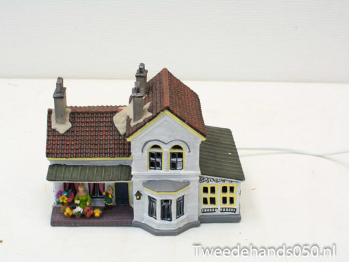 Charming miniature house with vibrant flowers and warm lighting for nostalgic decor.