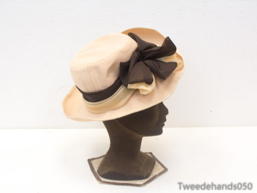 Sophisticated peach hat with contrasting black ribbon and oversized bow, perfect for vintage occasions.