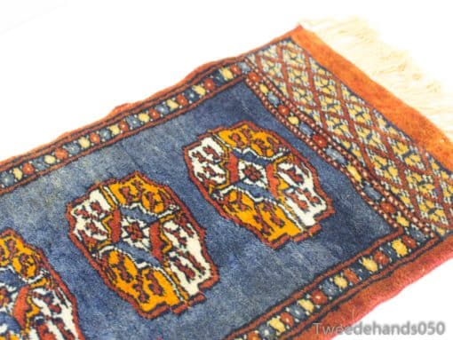 Handwoven vintage rug in deep blue with vibrant orange motifs, showcasing exquisite craftsmanship.