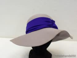 Sophisticated beige wide-brimmed hat with textured purple band, perfect for stylish summer events.