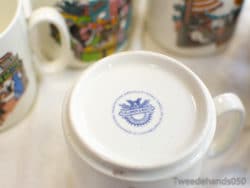 Elegant Haviland mug with blue logo surrounded by vibrant collectible ceramics.