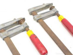 Vintage bar clamps with red ergonomic handles for wood and metalworking projects.