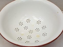 Vintage white colander with red rim, perfect for draining and rinsing fruits and pasta.