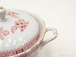 Elegant porcelain tureen with red floral patterns and gold trim, ideal for sophisticated dining.