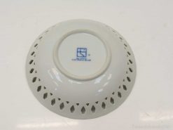 Elegant white porcelain bowl with intricate cutout design and blue insignia for serving or decor.