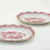 Elegant oval porcelain plates with gold rim and intricate red floral design for refined dining.