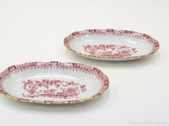 Elegant oval porcelain plates with gold rim and intricate red floral design for refined dining.