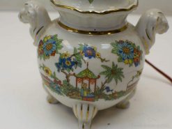 Vibrant porcelain vase with lion handles, floral designs, and gold accents in pagoda style.