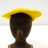 Cheerful yellow felt beret on sleek black mannequin, perfect for bold fashion statements.