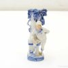 Charming porcelain boy figurine in sailor attire, playfully posed by a decorative grape column.