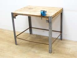 Rustic vintage workbench with metal legs and blue vise, ideal for woodworking and crafting projects.