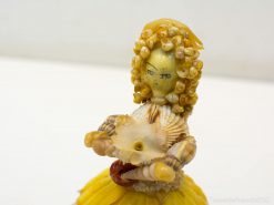 Whimsical handcrafted figurine with seashell hair and a vibrant yellow skirt for creative décor.