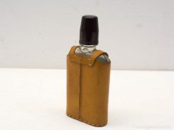 Stylish tan leather flask with modern glass body and secure black cap for discerning drinkers.