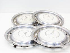 Set of four vintage Mercedes-Benz hubcaps with polished finish and classic three-pointed star logo.