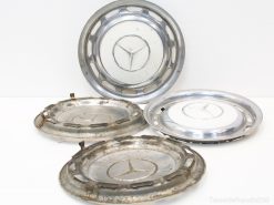 Vintage Mercedes hubcaps featuring iconic star emblem, showcasing wear and rich automotive history.