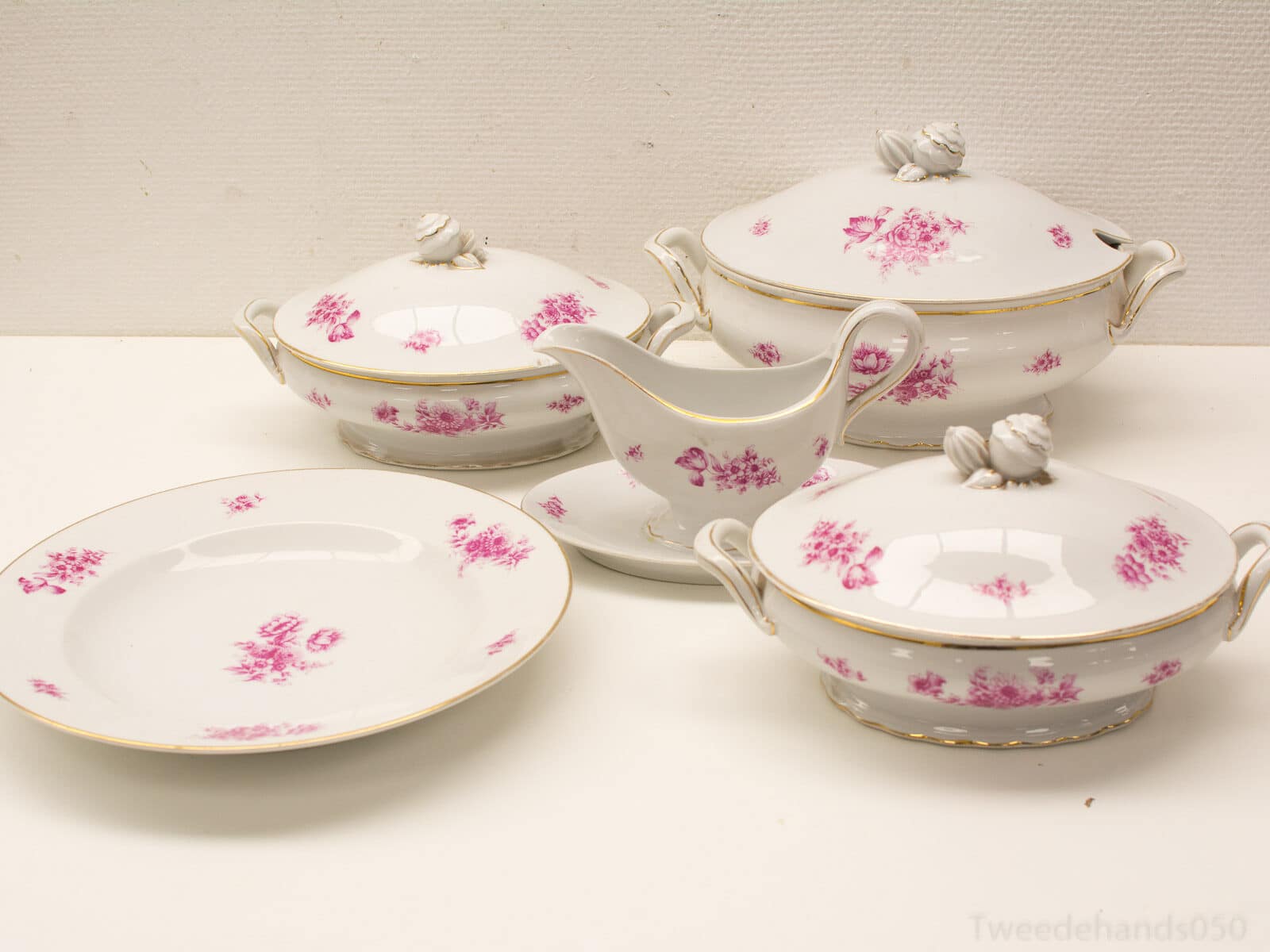 Elegant porcelain dish set with pink flowers and gold trim for refined dining experiences.