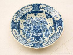 Elegant white ceramic bowl with intricate blue floral design and scalloped edges.