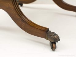 Elegant vintage wooden table leg with ornate brass claw, perfect for timeless interiors.