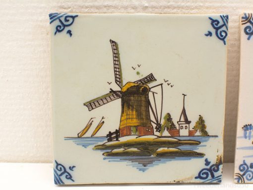 Charming ceramic tile featuring a traditional Dutch windmill and a peaceful village by water.