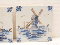 Dutch ceramic tile featuring a windmill, tranquil water, and floral motifs in classic blue and white.