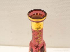 Elegant ruby red vase with gold rim and floral patterns, perfect for stylish decor and flowers.