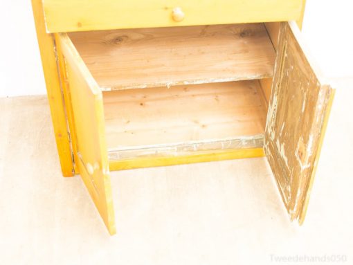 Cheerful yellow wooden cabinet with drawer and doors, ideal for cozy, rustic decor.