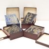 Elegant decorative plates with intricate blue and gold designs in luxurious wooden boxes.