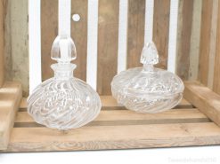 Elegant glass perfume bottles with swirling patterns on rustic wood, embodying vintage luxury and craftsmanship.