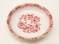 Elegant red and white porcelain plate with scalloped edge and intricate floral design.