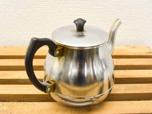 Elegant stainless steel kettle on wood, merging modern flair with vintage warmth for tea enthusiasts.