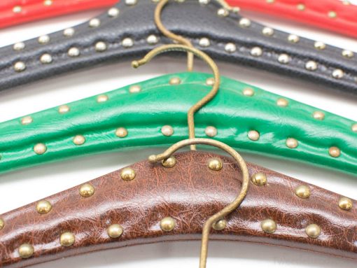 Vibrant vintage clothing hangers in red, black, green, and brown with brass accents.