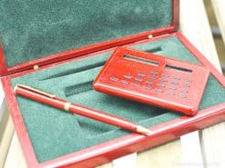 Sophisticated pen and calculator gift set in a polished wooden box with green velvet interior.